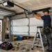 Technician repairing or installing a garage door with tools and safety equipment