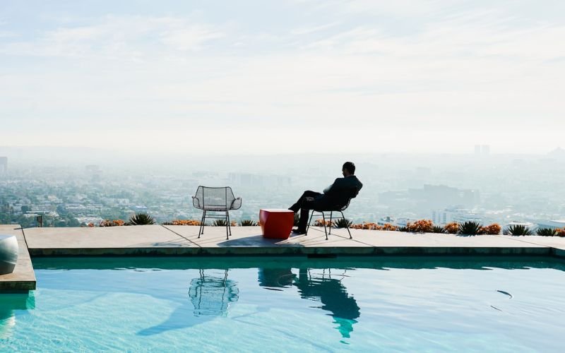 Person sitting near pool at Stahl House overlooking Los Angeles skyline