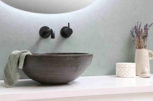 Minimalist bathroom sink with wall-mounted faucet, towel, and decorative items on countertop