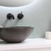 Minimalist bathroom sink with wall-mounted faucet, towel, and decorative items on countertop