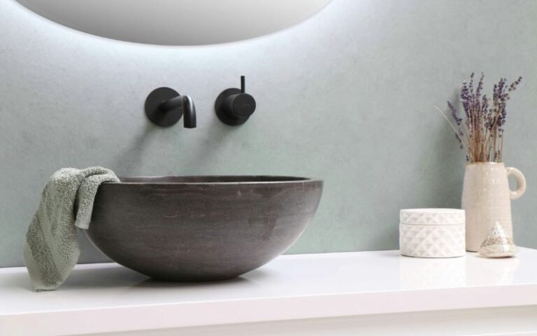 Minimalist bathroom sink with wall-mounted faucet, towel, and decorative items on countertop