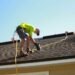 Worker inspecting roof shingles for maintenance and leak prevention