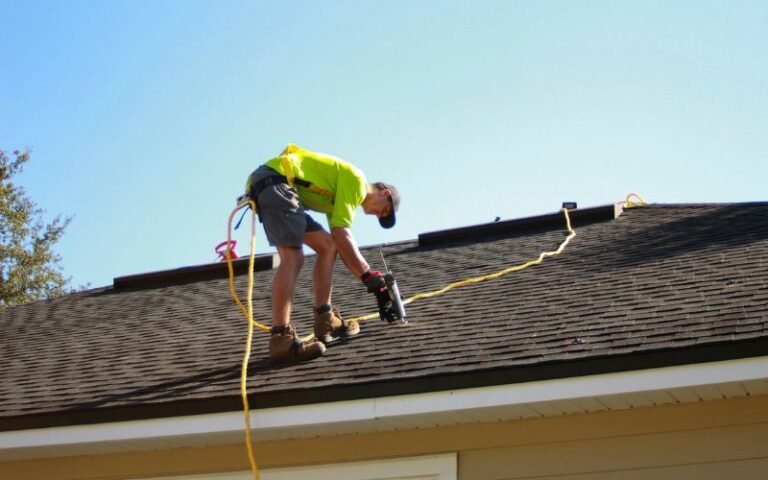 Worker inspecting roof shingles for maintenance and leak prevention