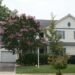 Two-story suburban house with driveway, garage, and trees in a calm residential neighborhood
