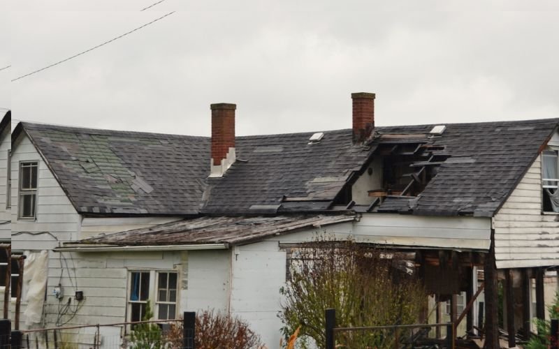 House damaged by natural disaster with broken roof and structural damage