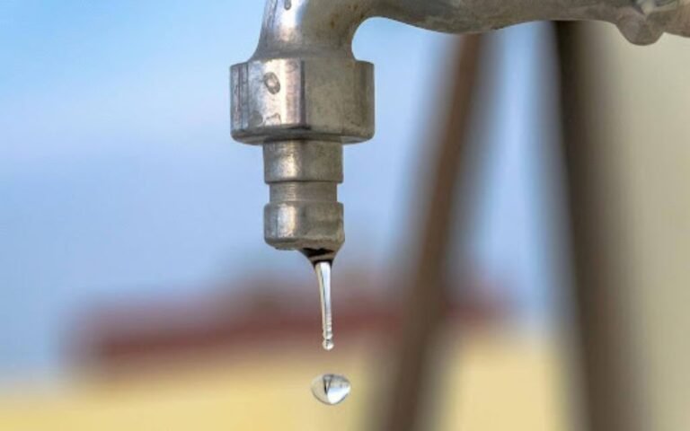 Water dripping from a metal tap showing a slow household leak