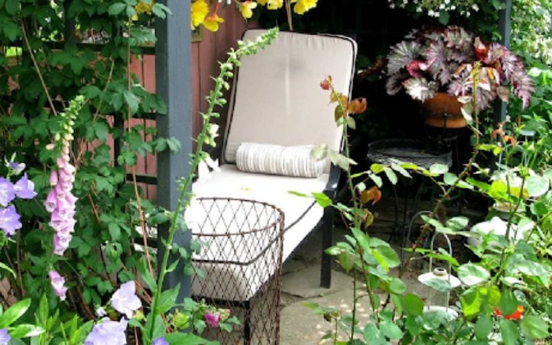 Small cozy garden nook with chair surrounded by lush plants and flowers