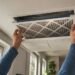 Homeowner replacing HVAC air filter in modern home ventilation system