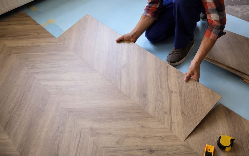Contractor installing modern wood-look flooring in a rental property renovation