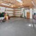Organized residential garage with wall shelving, storage racks, and open floor space