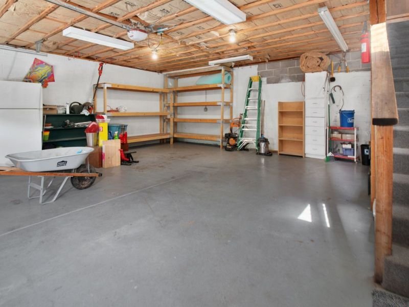 Organized residential garage with wall shelving, storage racks, and open floor space