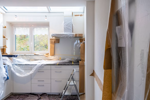 Partially renovated kitchen with cabinets covered in protective plastic during a remodeling project