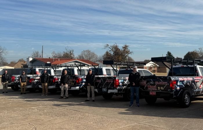 Professional roofing contractors standing beside company service trucks before residential roof inspections