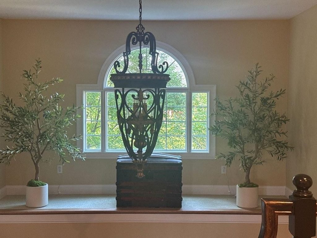 Twin faux olive trees flanking an arched window