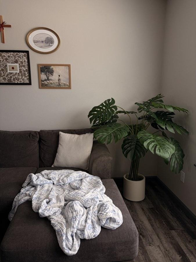 A faux monstera in a cozy, lived-in living room corner