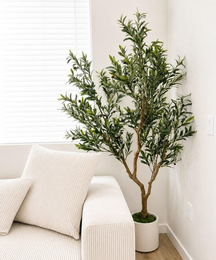 A faux olive tree beside a cream corduroy sofa